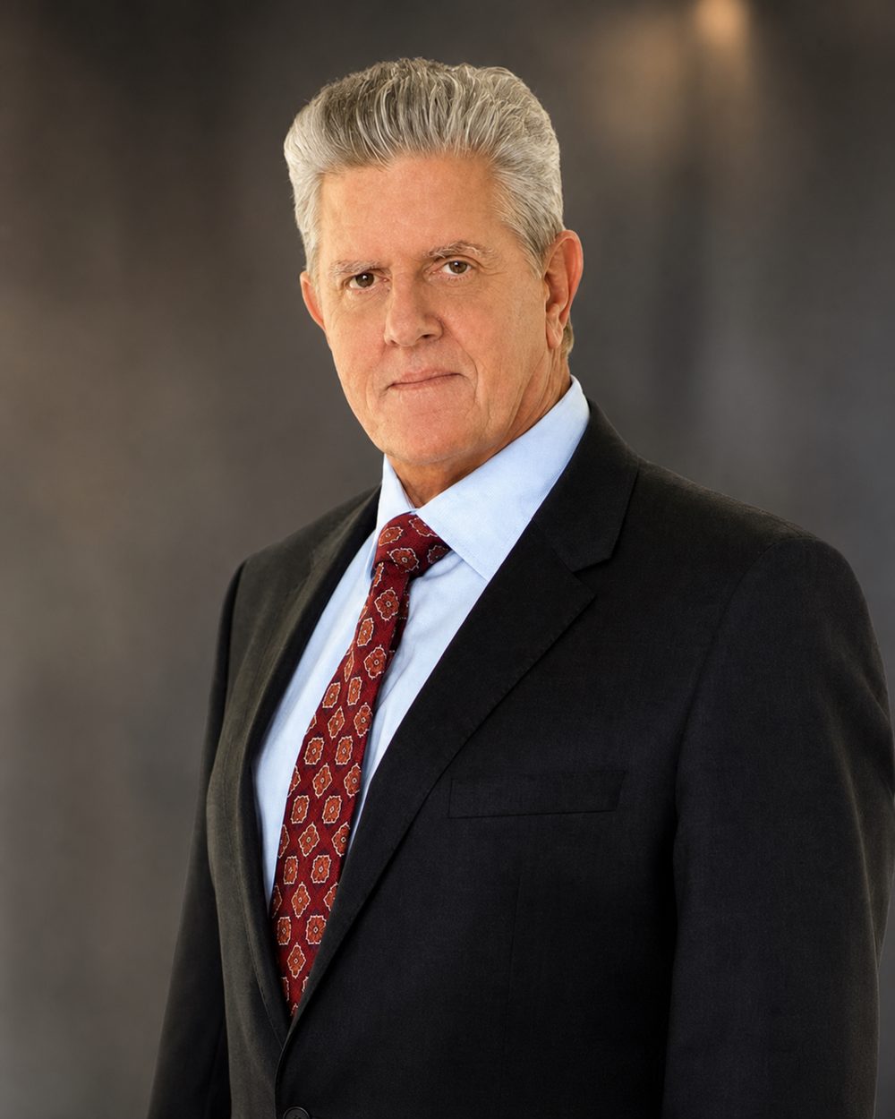 Studio headshot of Sam McMurray in a dark suit and blue shirt.